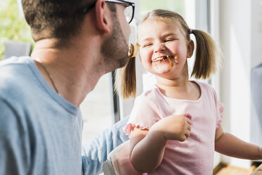 Verspielter Vater und Tochter mit Essen im Mund - UUF007440