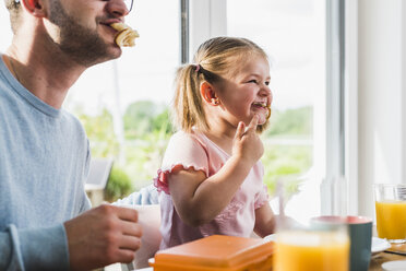 Verspielter Vater und Tochter mit Essen im Mund - UUF007441