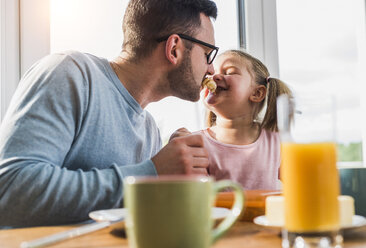 Verspielter Vater und Tochter mit Essen im Mund - UUF007442