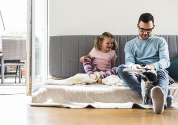 Father and daughter with dog at home - UUF007443