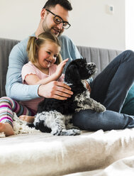 Father and daughter petting dog at home - UUF007444