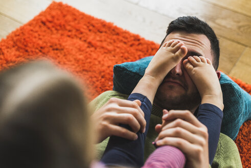 Verspielter Vater und Tochter liegen auf dem Teppich auf dem Boden - UUF007470