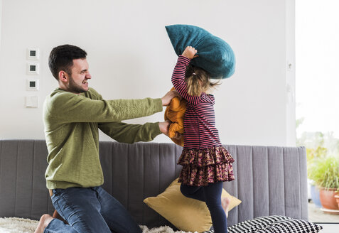 Vater und Tochter bei einer Kissenschlacht - UUF007473