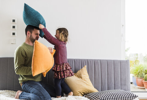 Vater und Tochter bei einer Kissenschlacht - UUF007474