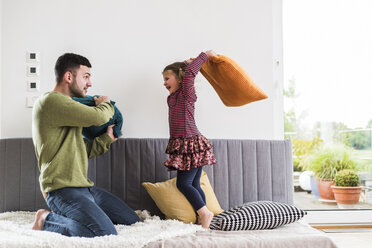 Father and daughter having a pillow fight - UUF007475