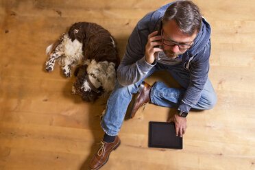 Overhead view of man on the phone on the floor next to dog - MAEF011755