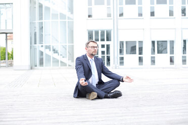 Businessman sitting outdoors meditating - MAEF011773