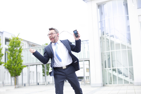 Enthusiastischer Geschäftsmann vor einem Bürogebäude, lizenzfreies Stockfoto