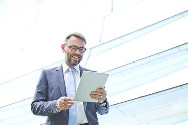 Smiling businessman using digital tablet outdoors - MAEF011786