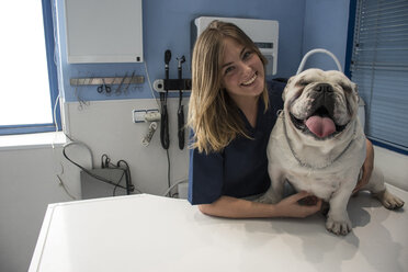 Porträt eines lächelnden Tierarztes mit Hund in einer Tierklinik - ABZF000629