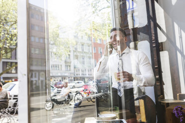 Glücklicher Geschäftsmann am Handy in einem Café - MADF000883