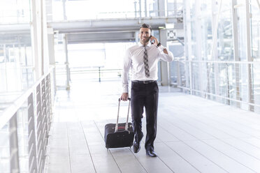 Businessman with luggage and cell phone on the move - MADF000884