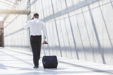 Businessman with luggage and cell phone on the move - MADF000890