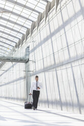 Businessman with luggage and cell phone on the move - MADF000891