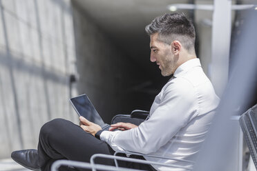 Businessman using digital tablet at waiting area - MADF000895