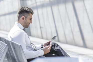 Businessman using digital tablet at waiting area - MADF000896