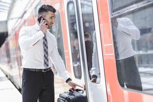 Geschäftsmann mit Handy beim Einsteigen in den Zug - MADF000897