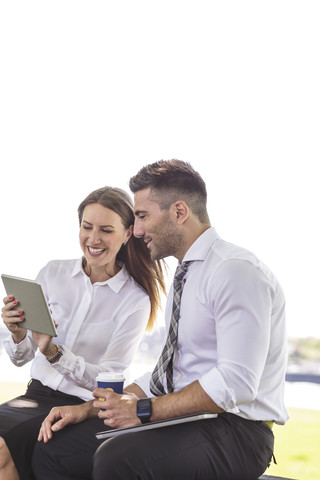 Businessman and businesswoman with digital tablet outdoors stock photo