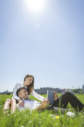 Happy business couple with digital tablet in meadow - MADF000913