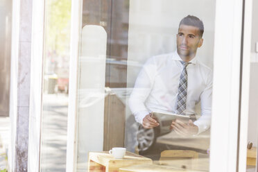 Businessman holding digital tablet in a cafe - MADF000917