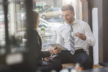 Businessman and businesswoman with digital tablet and smartphone in a cafe - MADF000921