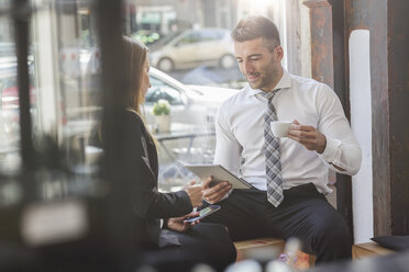 Geschäftsmann und Geschäftsfrau mit digitalem Tablet und Smartphone in einem Café - MADF000921