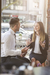 Businessman and businesswoman discussing in a cafe - MADF000923