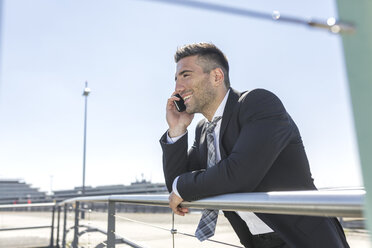 Smiling businessman on cell phone at the airport - MADF000934