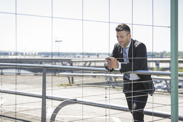 Businessman with cell phone at the airport - MADF000935