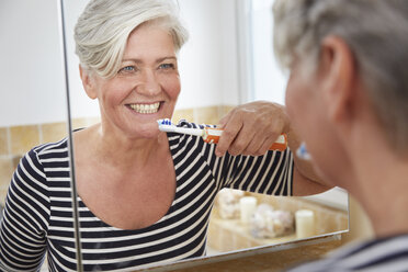 Mirror image of woman brushing her teeth - FMKF002731