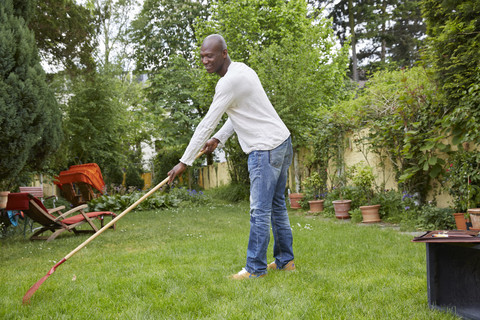 Mann harkend auf Wiese im Garten, lizenzfreies Stockfoto