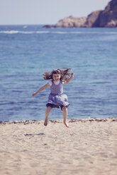 Spanien, glückliches kleines Mädchen, das am Strand in die Luft springt - XCF000094