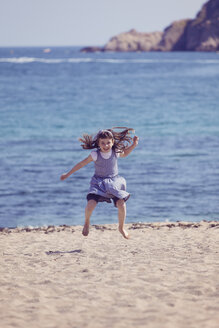 Spanien, glückliches kleines Mädchen, das am Strand in die Luft springt - XCF000094