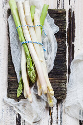 Tied green and white asparagus on old wooden board - SBDF002939