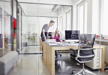 Man and woman working in office, smiling - RHF001496