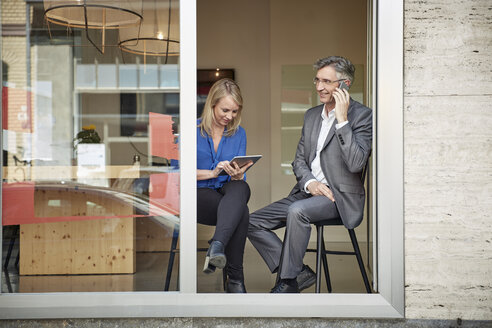 Geschäftsmann und Assistent arbeiten an der offenen Tür des Büros mit Smartphone und Tablet-PC - RHF001544