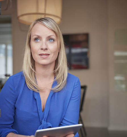 Frau sitzt im Büro und benutzt ein digitales Tablet, lizenzfreies Stockfoto