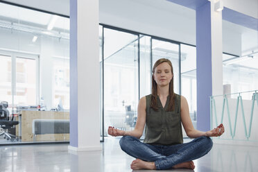 Businesswoman sitting cross -egged on floor, meditating - RHF001575