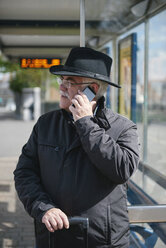 UK, Bristol, senior man telephoning with smartphone while waiting at bus stop - JCF000009