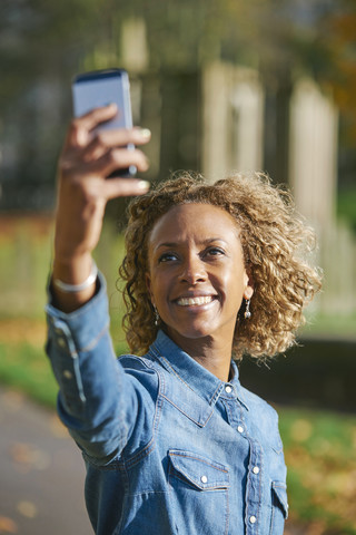 Porträt einer lächelnden Frau, die ein Selfie mit ihrem Smartphone macht, lizenzfreies Stockfoto