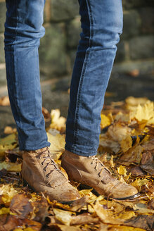 Woman wearing leather boots, standing on autumn leaves, partial view - JCF000019