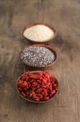 Three wooden bowls of dried wolfberries, chia and quinoa - ODF001387
