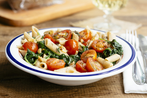 Vollkorn-Penne-Nudeln mit Spinat, Knoblauch und Tomaten, lizenzfreies Stockfoto