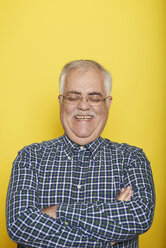 Portrait of smiling senior man with arms crossed and eyes closed in front of yellow background - JCF000031