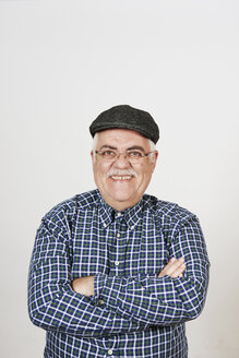 Portrait of smiling senior man with arms crossed in front of white background - JCF000039