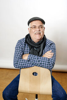 Portrait of smiling senior man sitting backwards on a chair - JCF000040