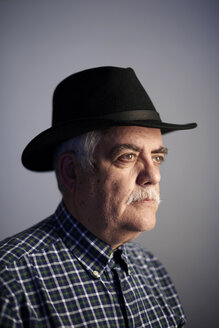 Portrait of serious senior man wearing black hat in front of grey background - JCF000042