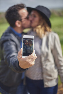 Selfie eines sich küssenden Paares auf dem Display eines Smartphones - JCF000047