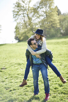 Man giving woman a piggyback ride on a meadow - JCF000052