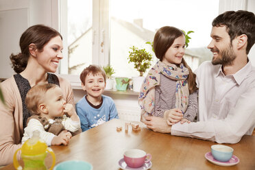 Happy family of five sitting at table at home - MFF002973